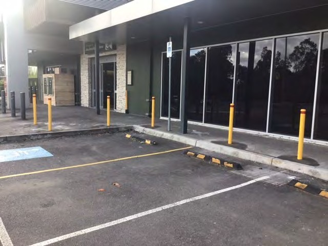 Bollards along a shopfront behind parking bays and wheel stops