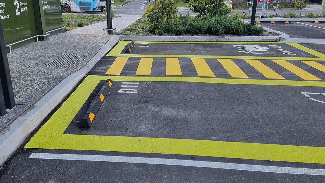 Yellow bay lines, hatching and rubber wheel stops in a store car park