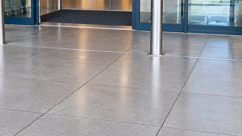 Tiled store entry after pressure cleaning, with stainless bollards at the doors