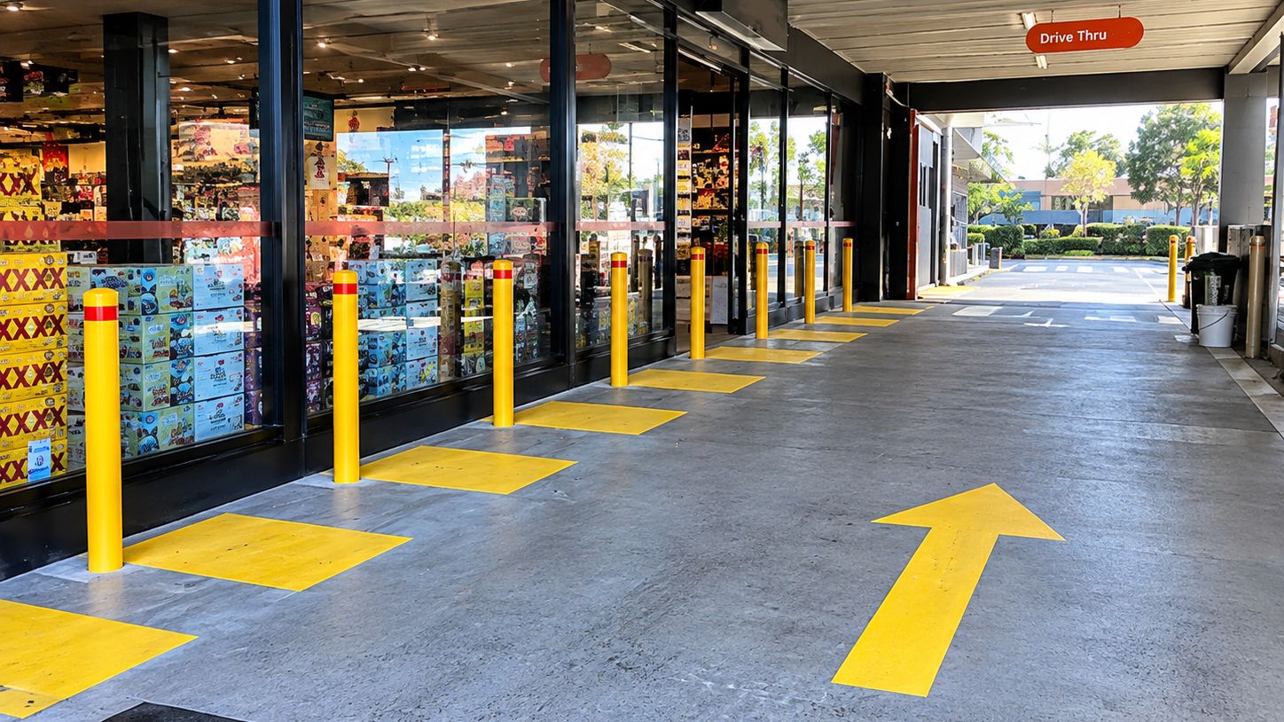 Yellow steel bollards along a drive thru shopfront