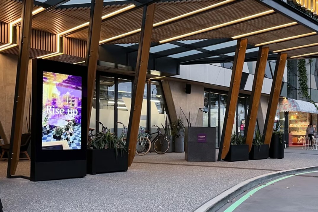 Entrances and canopies: The same outdoor rated kiosk placed where people arrive: under a canopy, at a centre entrance or beside a drop off zone.
