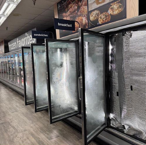 A run of supermarket freezer doors with heavy condensation across every pane