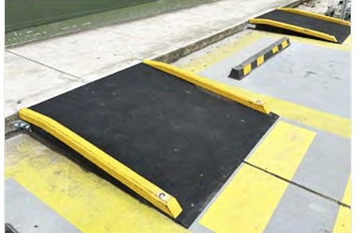 Two kerb ramps with yellow side kerbing, one at each marked bay