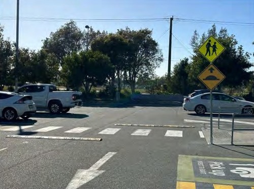 A pedestrian crossing sign above a speed hump sign on one pole, at a crossing