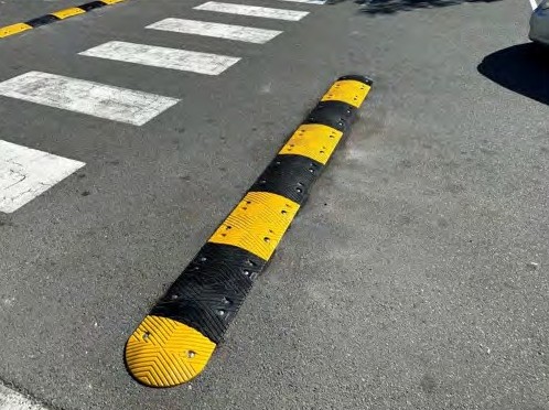 A rubber speed hump beside a pedestrian crossing