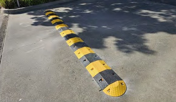 A yellow and black rubber speed hump across a driveway