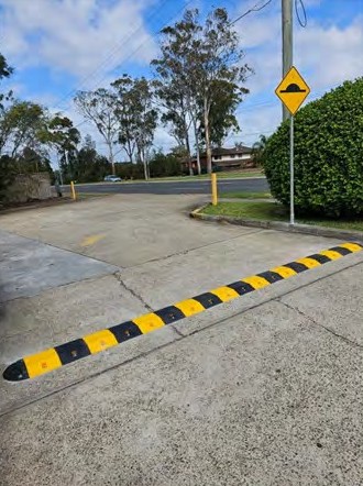 A speed hump across a car park lane, with a hump warning sign