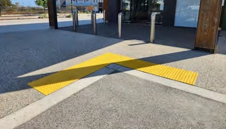 Yellow tactiles across the approach to a store entry