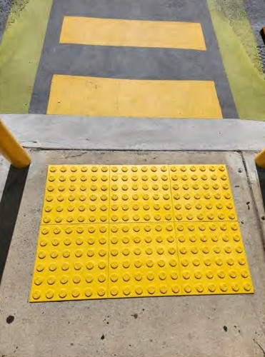Yellow warning tactile tiles at the end of a pedestrian crossing
